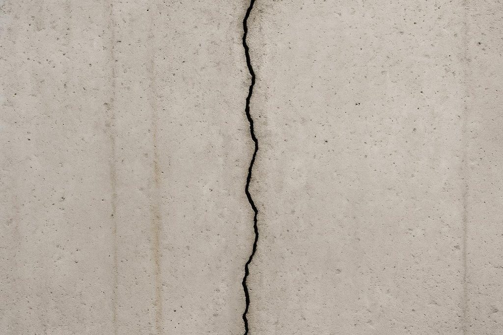 Vertical hairline crack in a poured concrete basement foundation wall