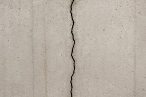 Vertical hairline crack in a poured concrete basement foundation wall