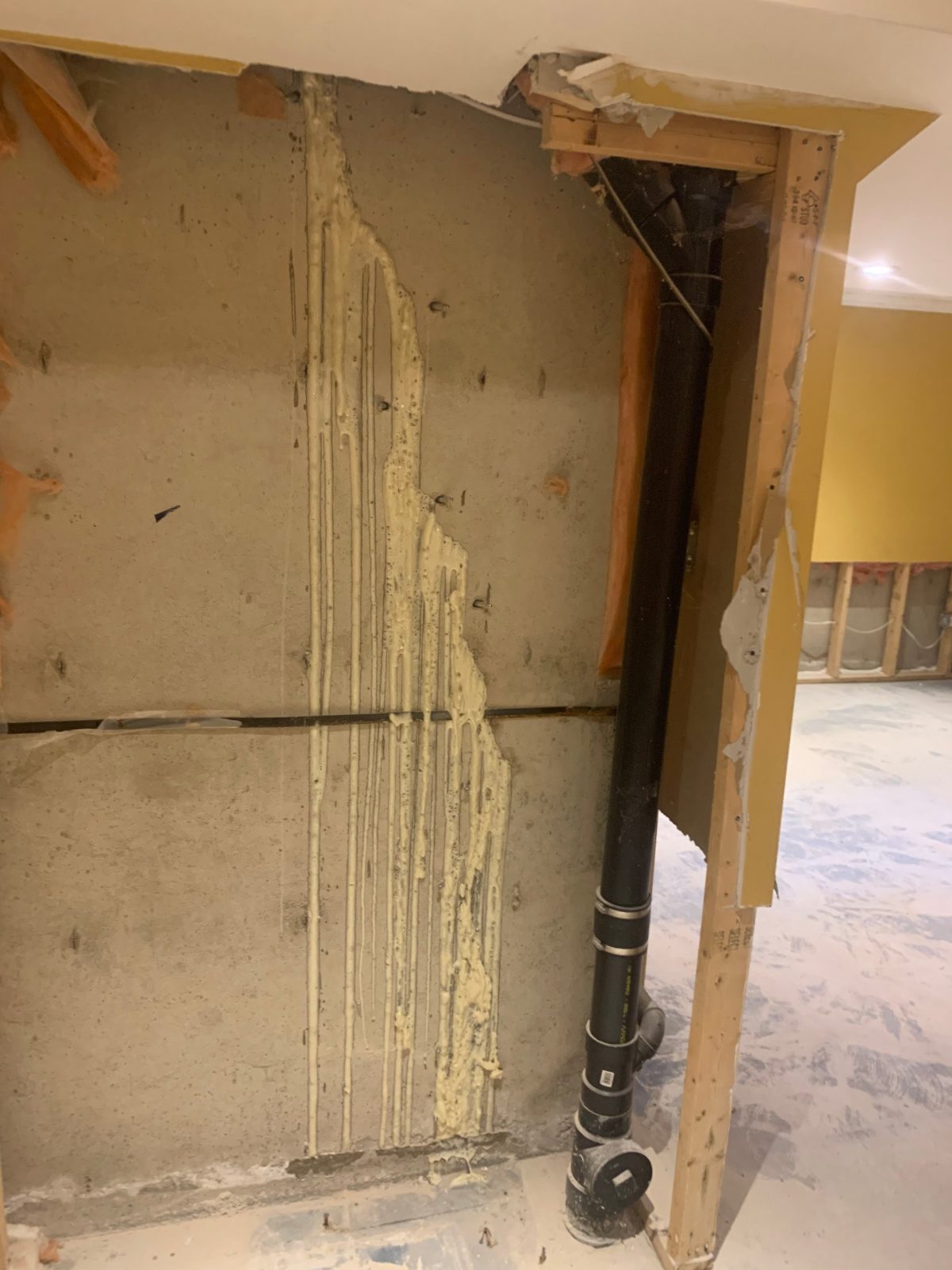 Vertical basement wall crack beside a plumbing stack after polyurethane crack injection