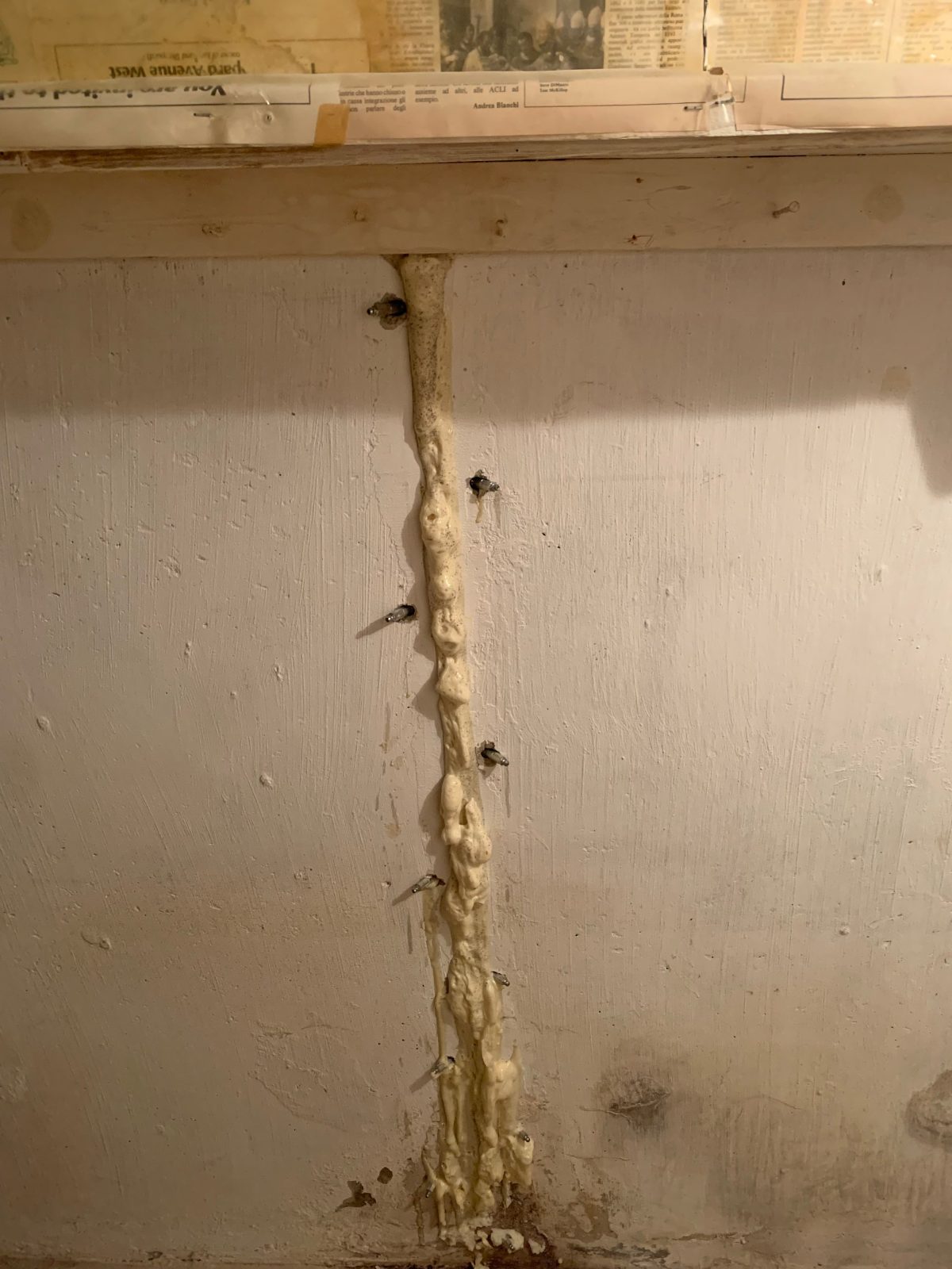Vertical foundation crack in a painted basement wall after polyurethane injection through ports